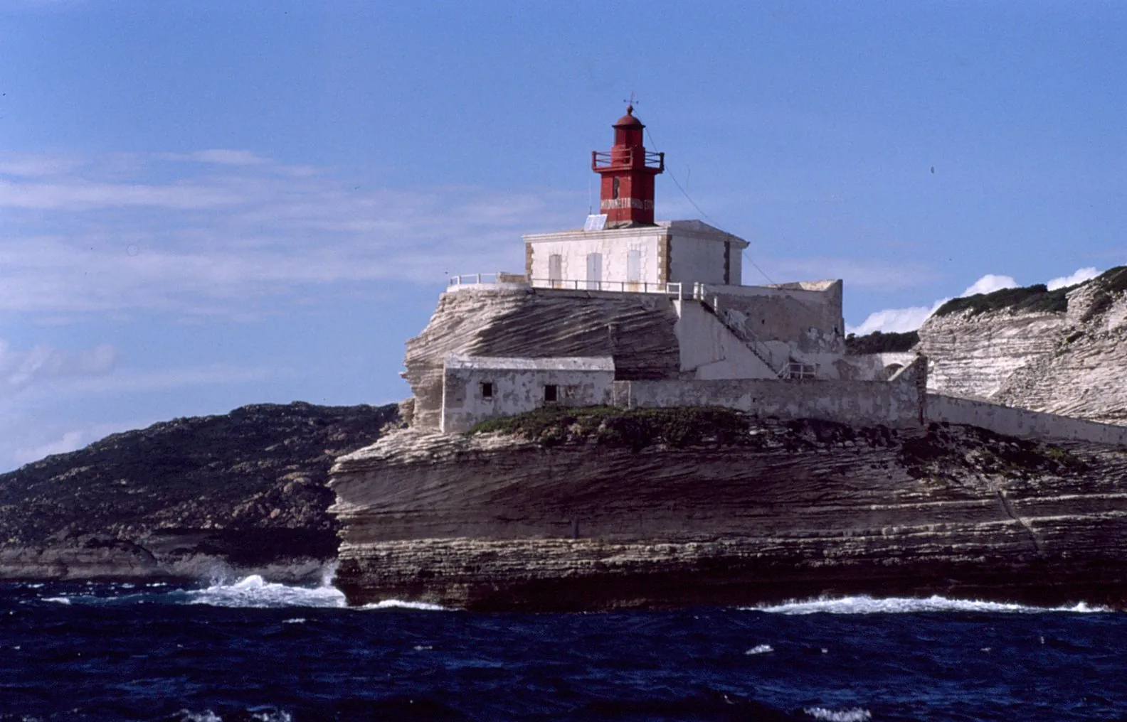 Leuchtturm auf einer felsigen Landzunge vor Sardinien