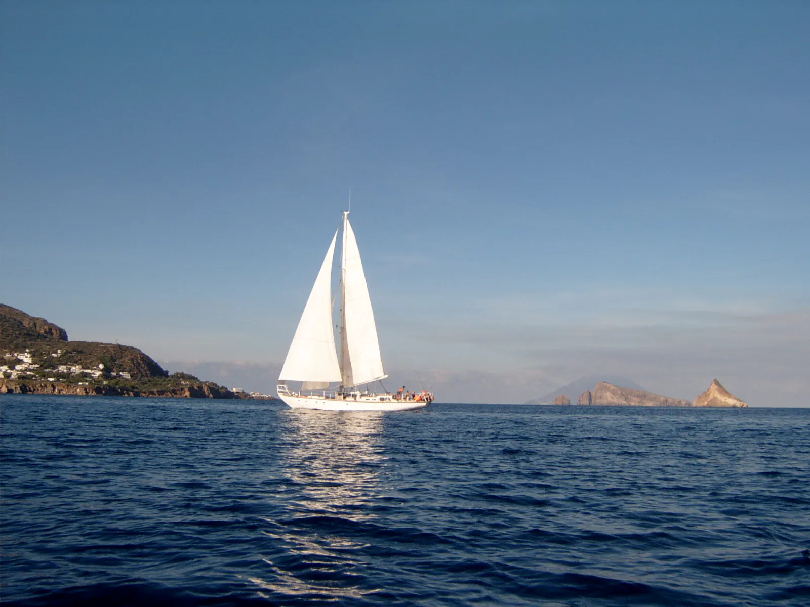 Segelyacht unter weissen Segeln vor der Küste Sardiniens